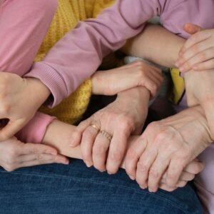 Multiple arms intertwined, symbolizing family unity and support across generations.